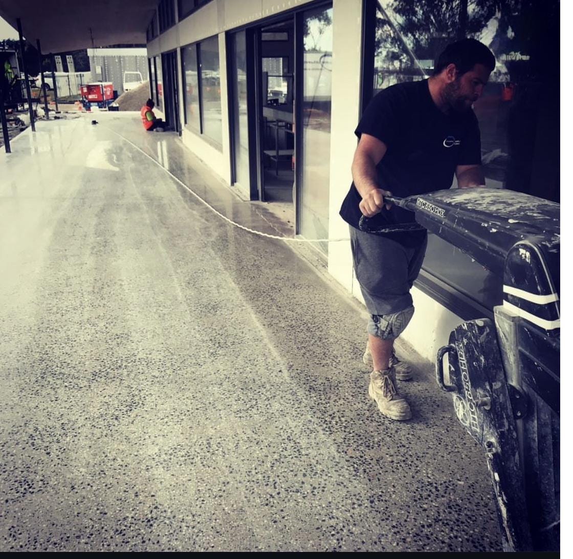 CHA operator grinding a concrete walkway to remove adhesive and prepare the surface